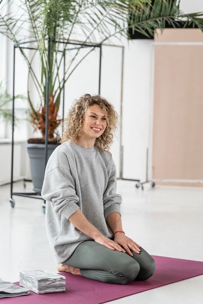 Mujer sonriente de tiro completo en estera de yoga