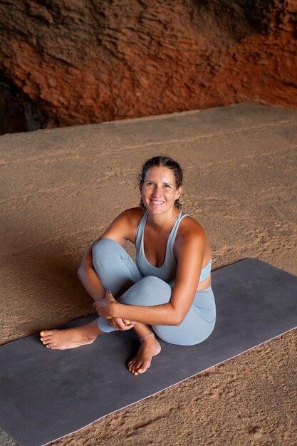 Mujer sonriente de tiro completo en estera de yoga