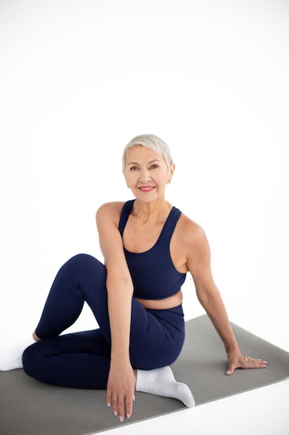 Mujer sonriente de tiro completo en estera de yoga