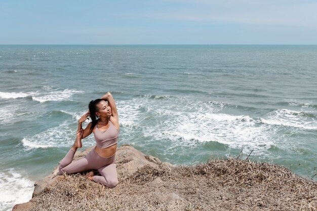 Mujer sonriente de tiro completo haciendo yoga al aire libre