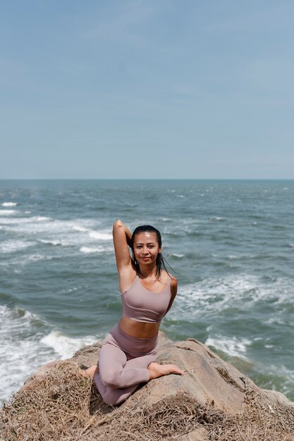 Mujer sonriente de tiro completo haciendo yoga en la naturaleza