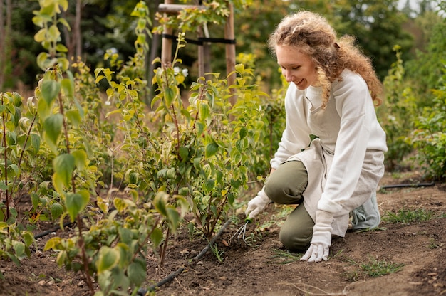 Foto gratuita mujer sonriente de tiro completo jardinería