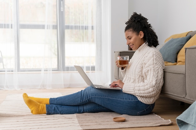 Foto gratuita mujer sonriente de tiro completo con laptop