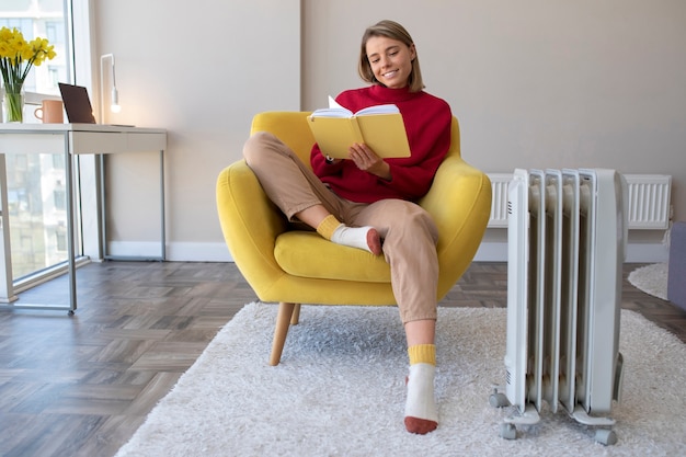 Foto gratuita mujer sonriente de tiro completo leyendo en casa