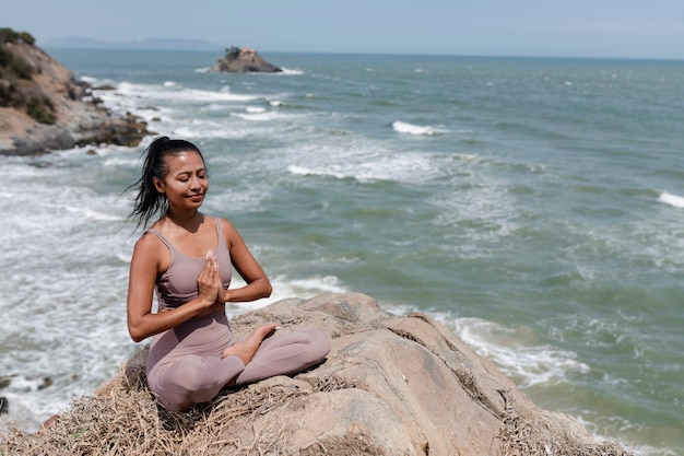 Mujer sonriente de tiro completo meditando al aire libre