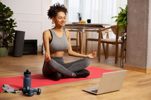 Mujer sonriente de tiro completo meditando