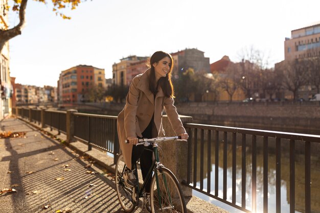 Mujer sonriente de tiro completo montando bicicleta