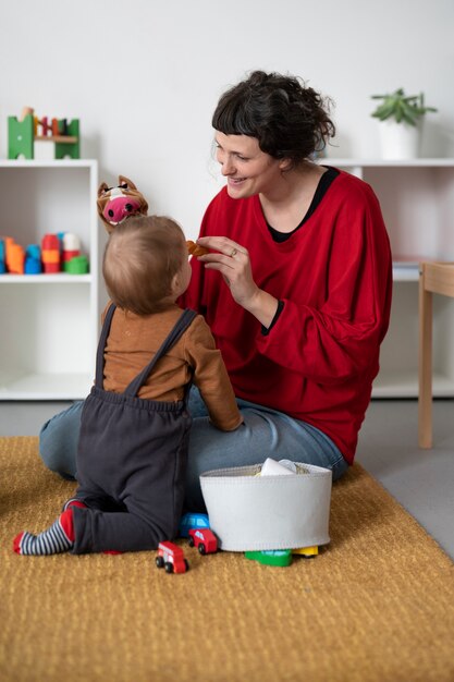 Mujer sonriente de tiro completo con niño pequeño