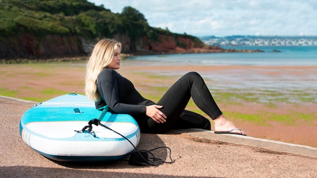 Mujer sonriente de tiro completo con paddleboard