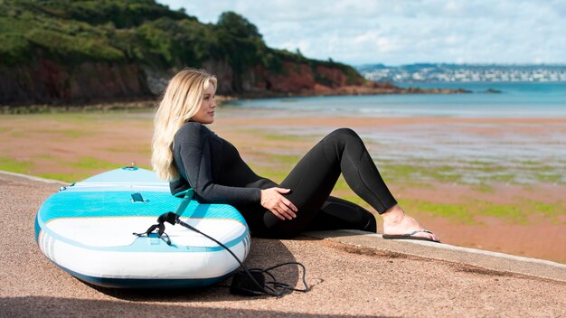 Mujer sonriente de tiro completo con paddleboard