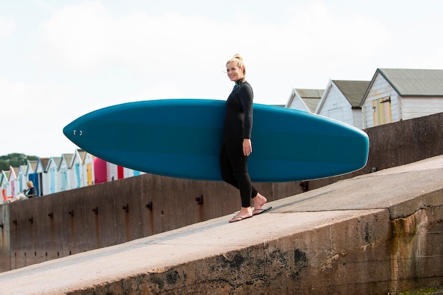 Foto gratuita mujer sonriente de tiro completo con paddleboard