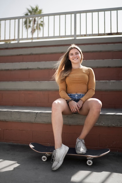 Mujer sonriente de tiro completo con patineta