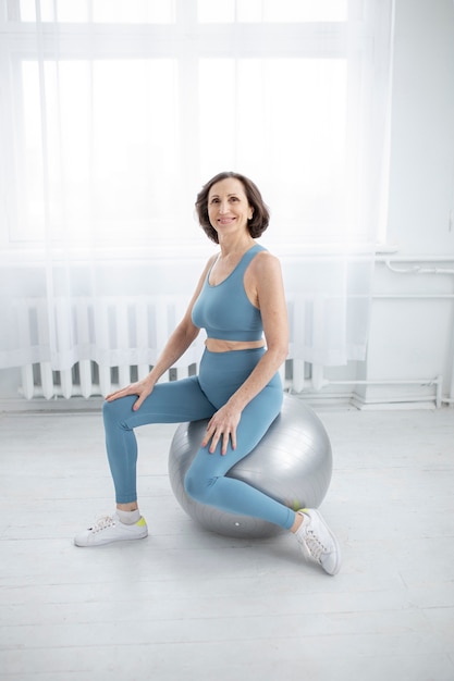 Foto gratuita mujer sonriente de tiro completo en pelota de gimnasia