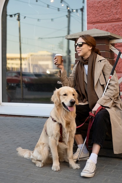 Mujer sonriente de tiro completo con perro de servicio