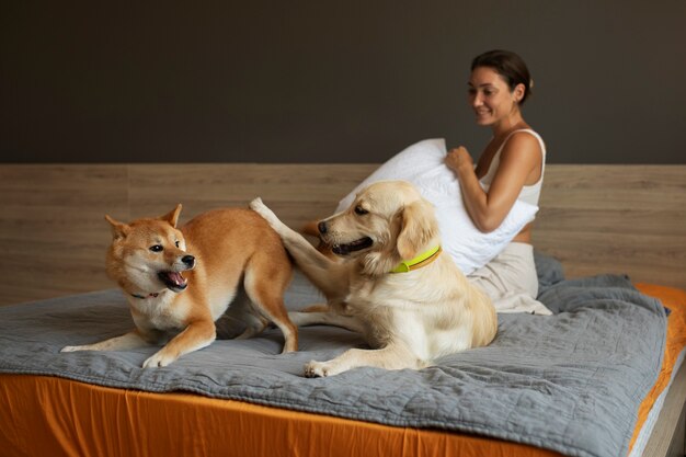 Mujer sonriente de tiro completo y perros en la cama