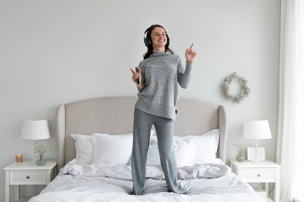 Mujer sonriente de tiro completo de pie en la cama