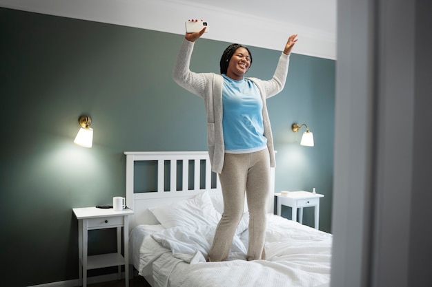 Foto gratuita mujer sonriente de tiro completo de pie en la cama