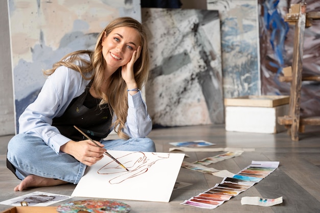 Foto gratuita mujer sonriente de tiro completo pintura sobre lienzo