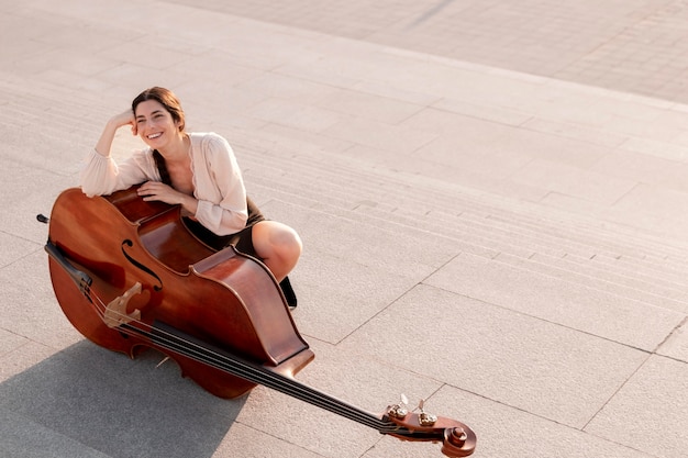 Mujer sonriente de tiro completo posando con contrabajo