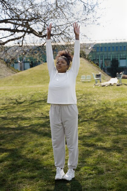 Mujer sonriente de tiro completo que se extiende al aire libre