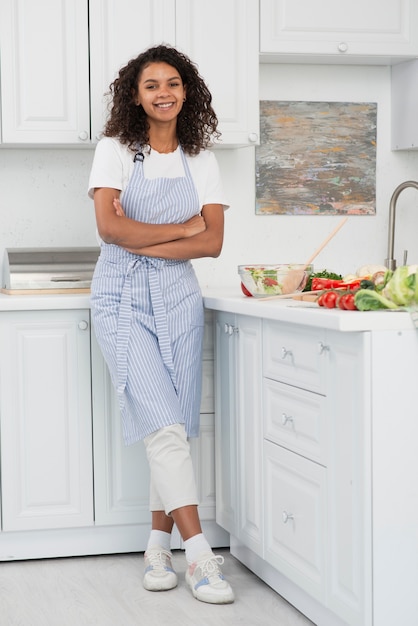 Mujer sonriente de tiro completo sentada en la cocina