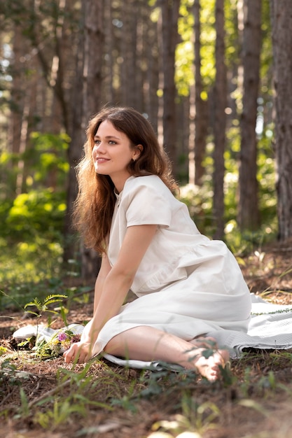 Foto gratuita mujer sonriente de tiro completo sentada en una manta