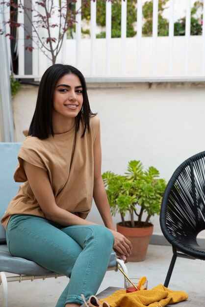 Mujer sonriente de tiro completo sentada en una silla