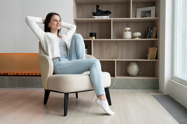 Mujer sonriente de tiro completo sentada en una silla