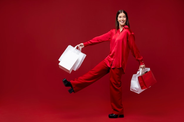 Mujer sonriente de tiro completo sosteniendo bolsas de la compra.