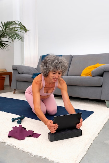 Mujer sonriente de tiro completo con tableta