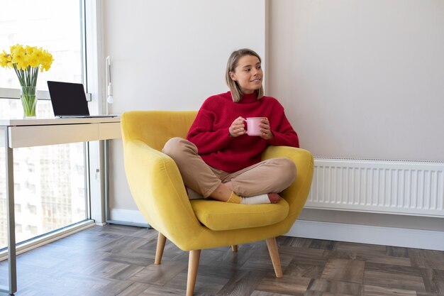 Mujer sonriente de tiro completo con taza de café