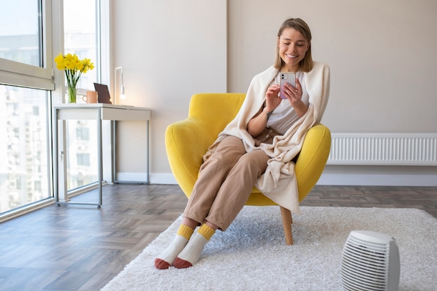 Mujer sonriente de tiro completo con teléfono inteligente