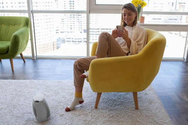 Mujer sonriente de tiro completo con teléfono inteligente