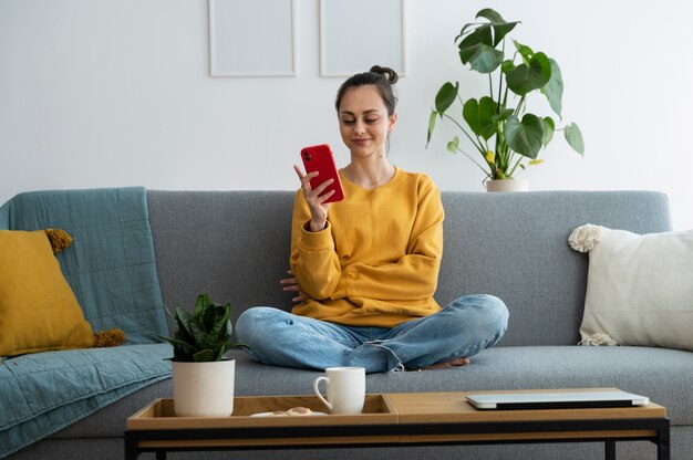 Mujer sonriente de tiro completo con teléfono inteligente