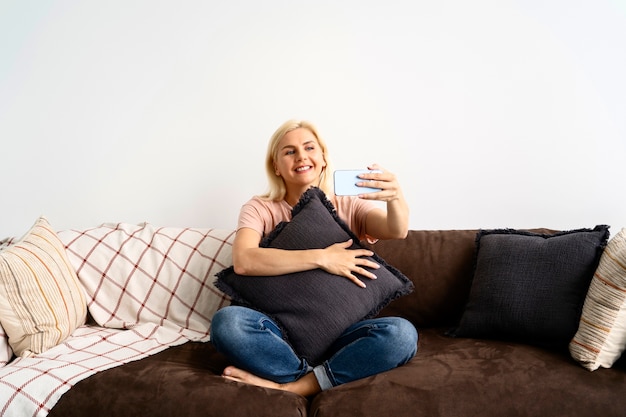 Mujer sonriente de tiro completo con teléfono inteligente