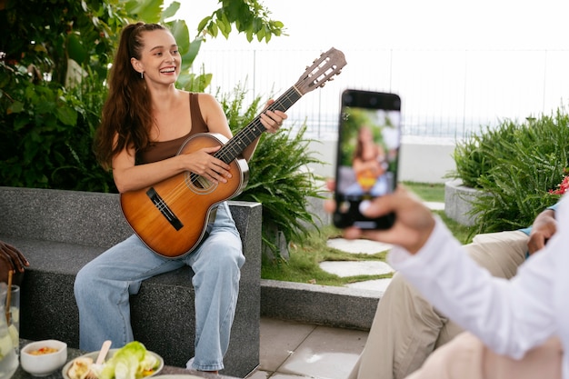 Mujer sonriente de tiro completo tocando la guitarra