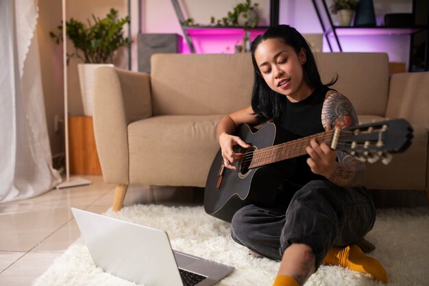 Mujer sonriente de tiro completo tocando la guitarra