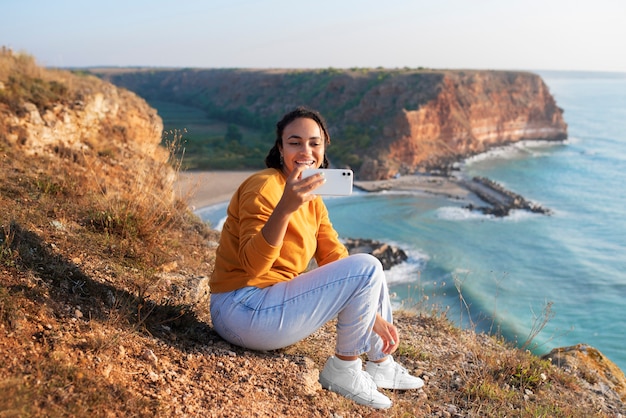 Mujer sonriente de tiro completo tomando selfie al aire libre