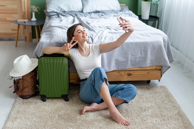 Foto gratuita mujer sonriente de tiro completo tomando selfie