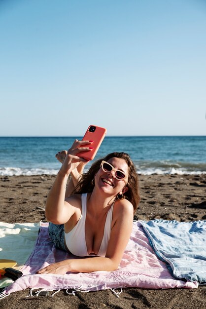 Mujer sonriente de tiro completo tomando selfie