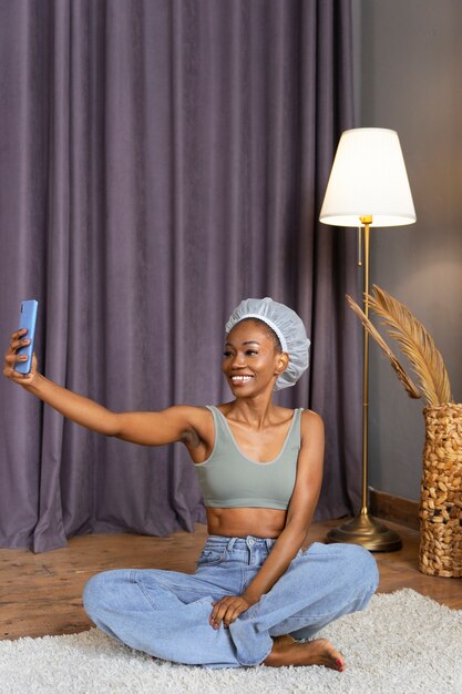 Mujer sonriente de tiro completo tomando selfie