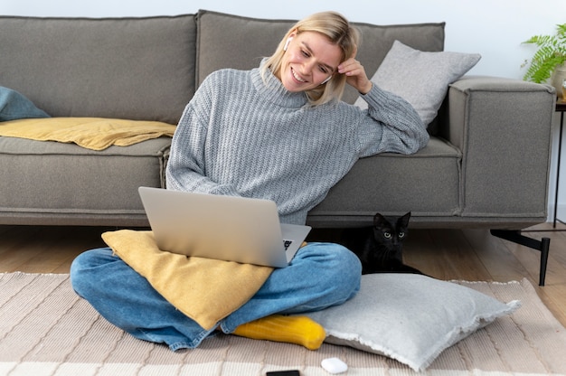 Mujer sonriente de tiro completo trabajando desde casa