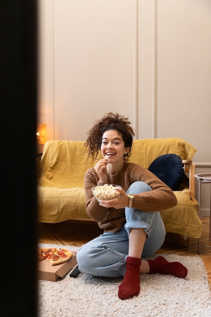 Foto gratuita mujer sonriente de tiro completo viendo la televisión