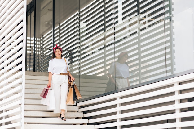 Mujer sonriente de tiro largo caminando por las escaleras