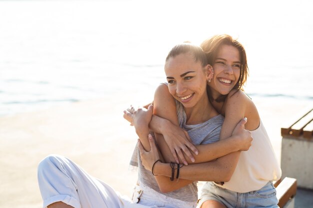 Mujer sonriente de tiro medio abrazando a su amiga