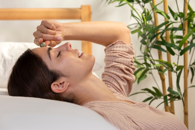 Mujer sonriente de tiro medio acostada en la cama con cristal