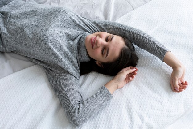 Mujer sonriente de tiro medio acostada en la cama