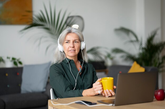 Mujer sonriente de tiro medio con auriculares en el escritorio