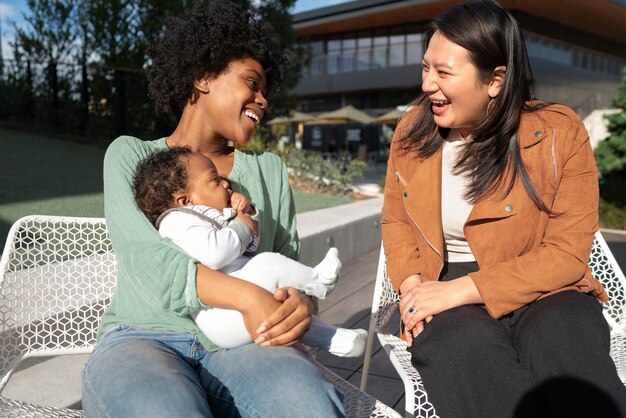 Mujer sonriente de tiro medio y bebé afuera