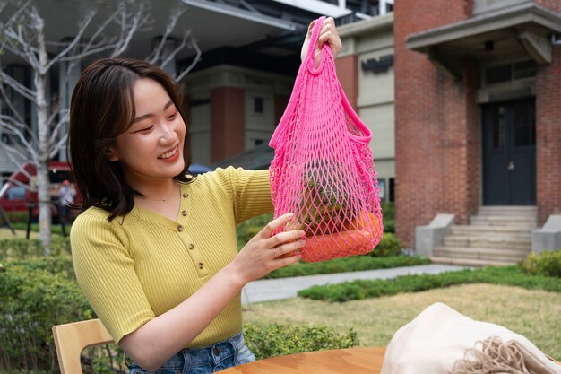 Mujer sonriente de tiro medio con bolsa de tela rosa.